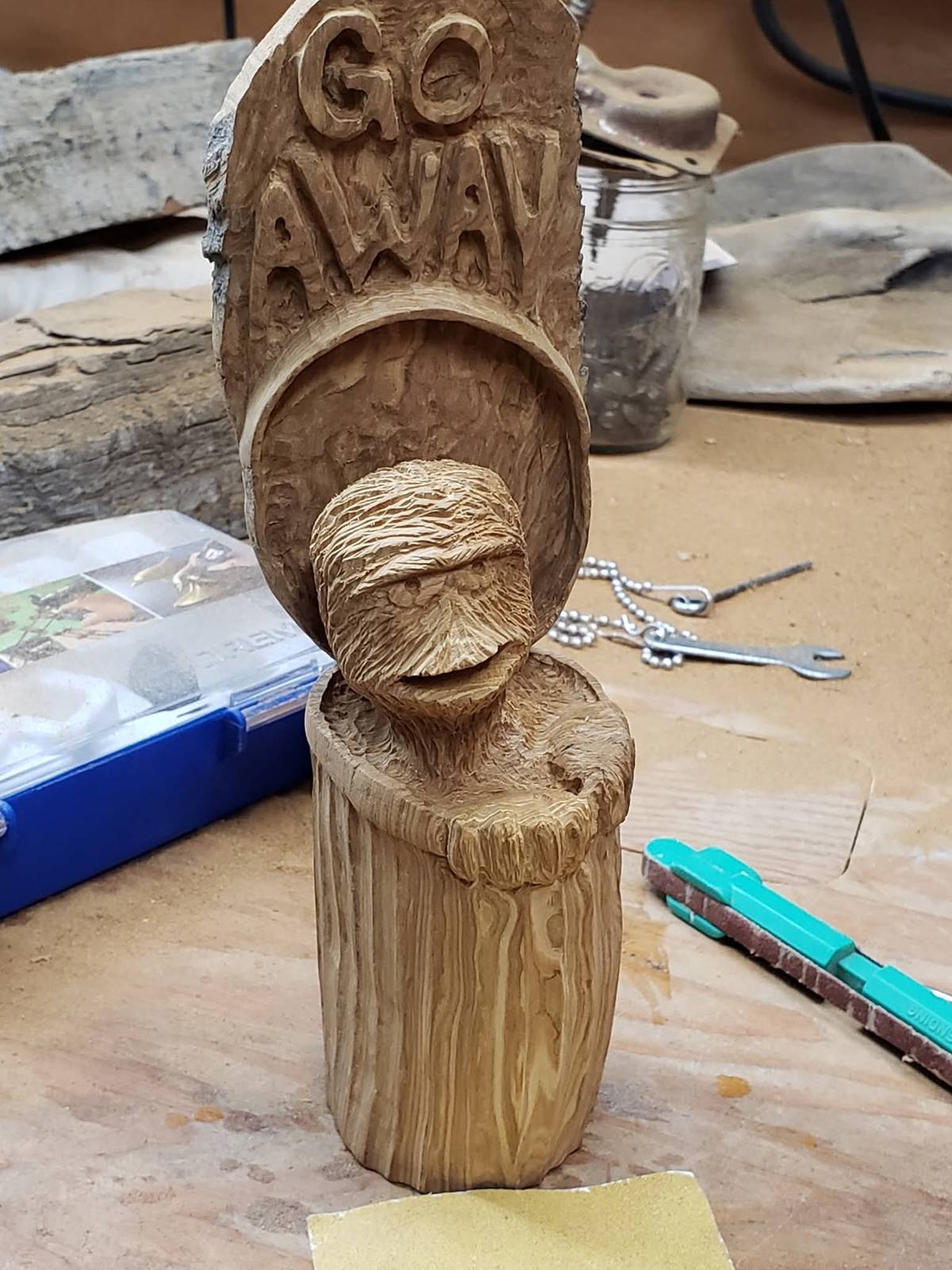 Carving of Oscar the Grouch popping out of a stump under a Go Away sign